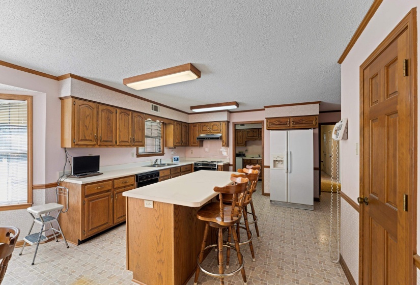 Galley-style kitchen featuring abundant cabinetry, a center island with seating, breakfast area, and windows overlooking the scenic property.