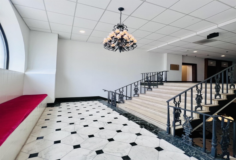 Grand entrance featuring a chandelier, black and white geometric floor tiling, and a built-in bench