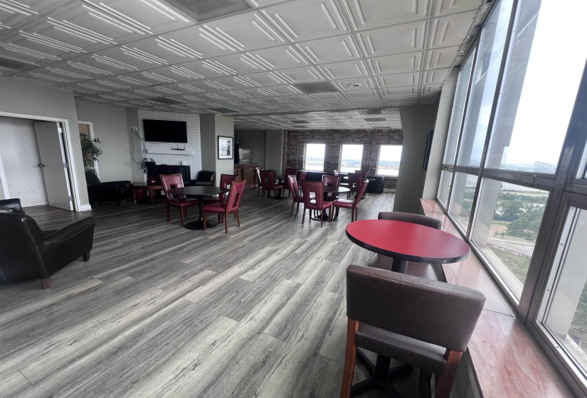 Spacious common area featuring textured ceiling panels, wood-finish flooring, and large windows