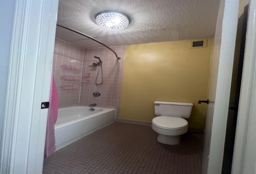 Bathroom featuring a white bathtub, pink tiled shower surround, and a white toilet