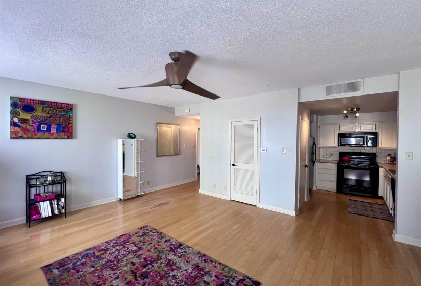 Open-concept living area featuring wood-finish flooring, a contemporary ceiling fan, and a neutral color palette
