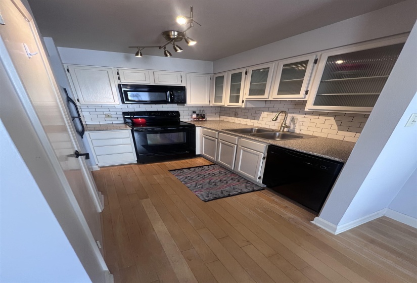 Kitchen featuring white cabinetry, subway tile backsplash, and light wood-finish flooring