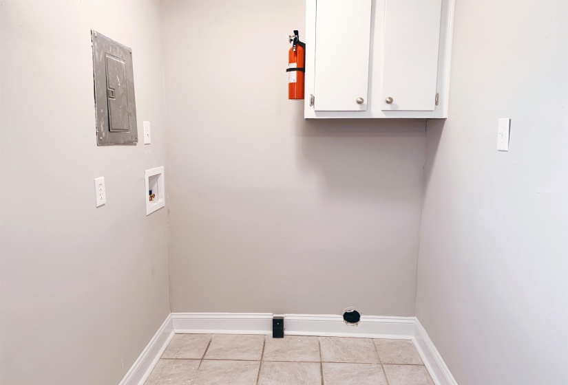 Laundry room featuring cabinet space, washer hookup, electric panel, and light tile patterned flooring