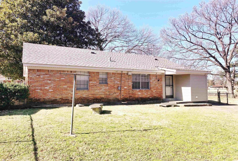 Back of property with brick siding and roof with shingles