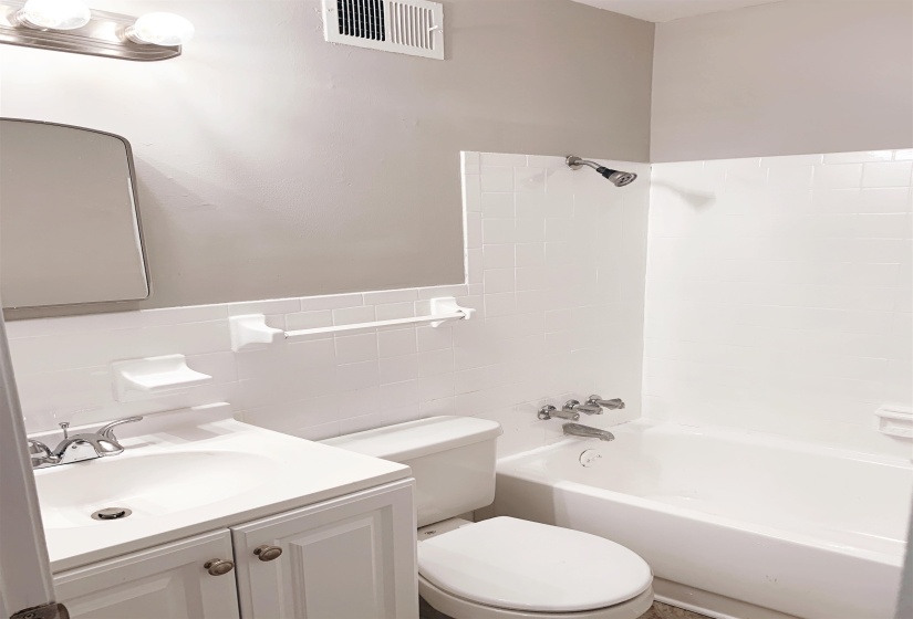 Full bathroom with vanity, shower / tub combination, tile walls, and a wainscoted wall