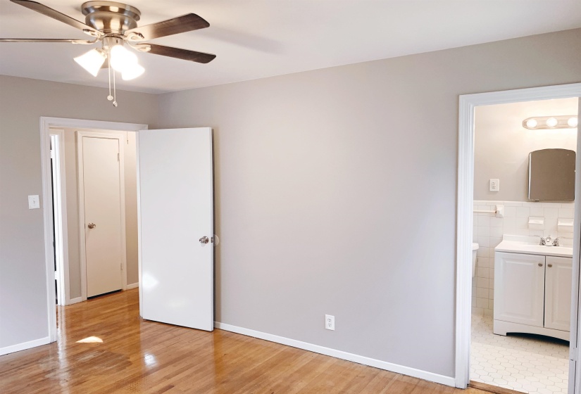 Unfurnished bedroom with ceiling fan, light wood-type flooring, and ensuite bathroom