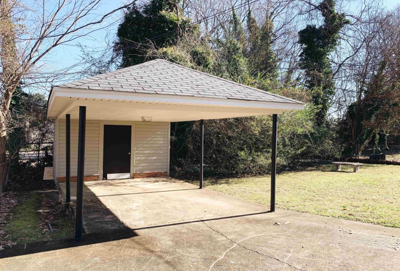 View of outbuilding featuring concrete driveway and a carport