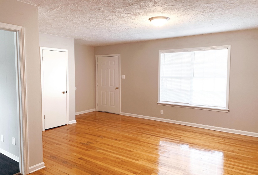 Empty room with light wood finished floors and a textured ceiling