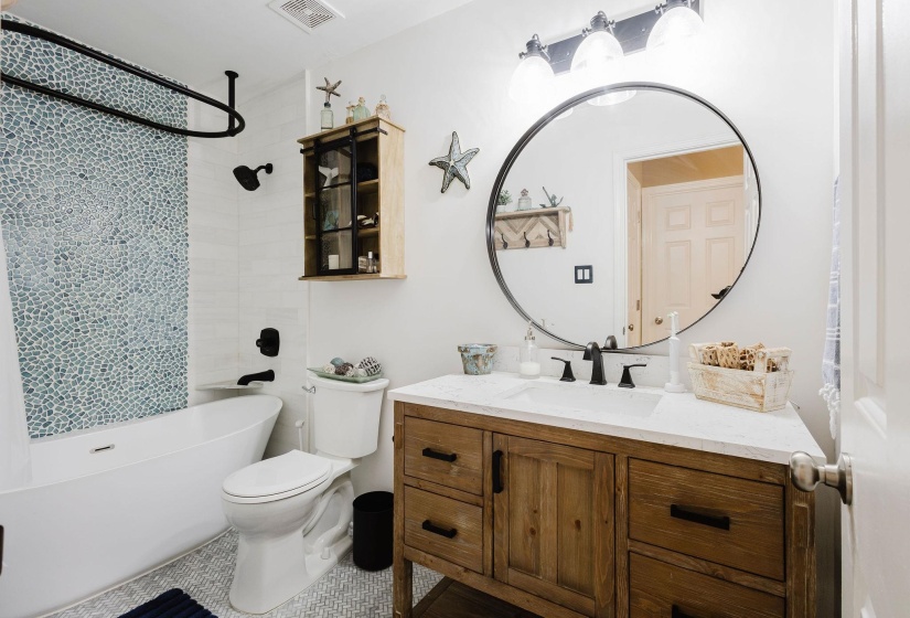 Modern bathroom featuring a wood-finish vanity with a single basin sink, white countertop, and matte black fixtures