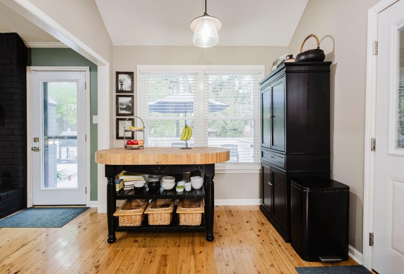 Warm wood-finish flooring complements the vaulted ceiling and natural light from the large window