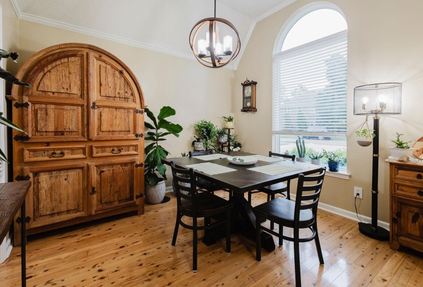 Arched window with blinds, vaulted ceiling, wood-finish flooring, and a contemporary chandelier