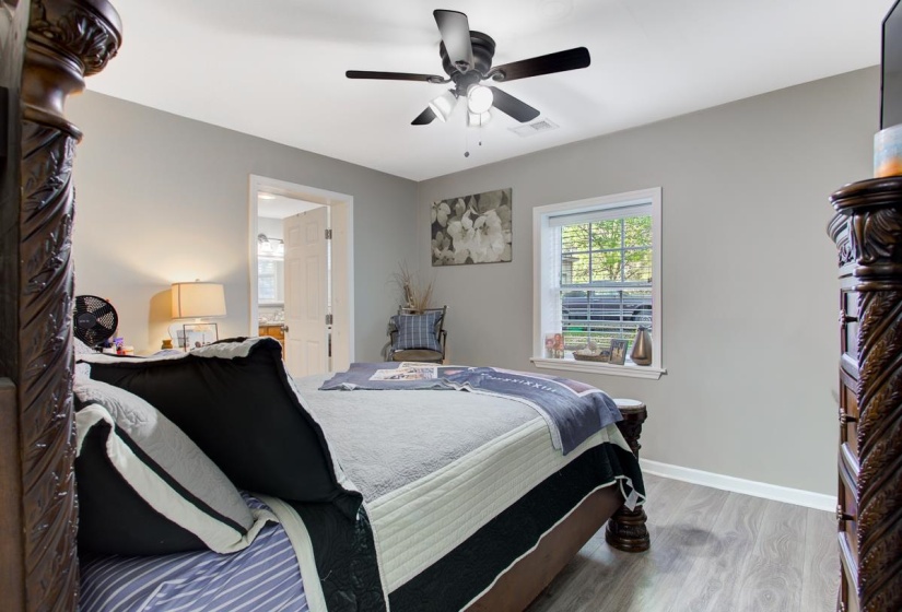 Bedroom featuring light LVP flooring, connected bathroom, and a ceiling fan