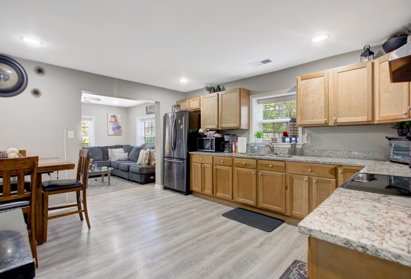 Kitchen with stainless steel appliances, light LVP flooring, light stone counters, light wood finish cabinets, and recessed lighting