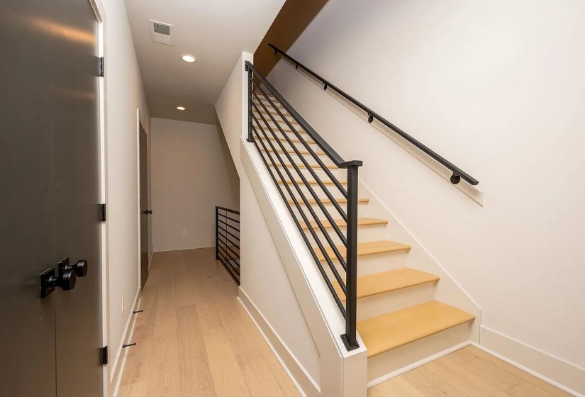 Modern staircase featuring light wood treads and a contemporary black metal railing