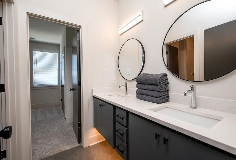 Double vanity featuring integrated sinks, white countertops, and dark cabinetry with matte black hardware