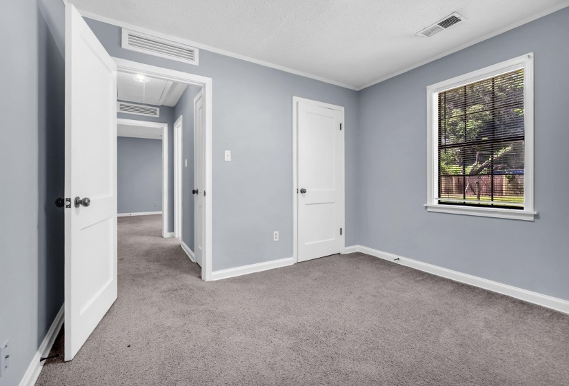 Room featuring light gray walls, gray carpet, white trim, and a window with black blinds