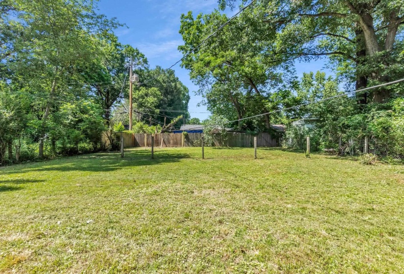 Expansive grassy yard area with partial wood privacy fencing