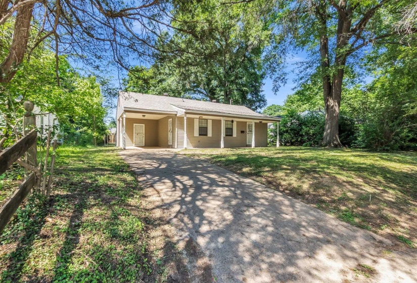 Single-story residence featuring a covered front porch with white columns, a carport, and a gravel driveway