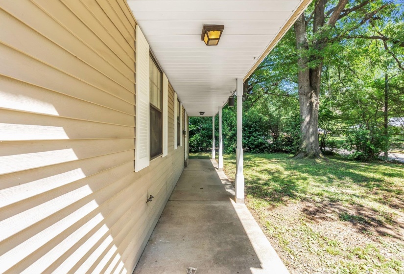 Covered concrete porch with tan horizontal siding