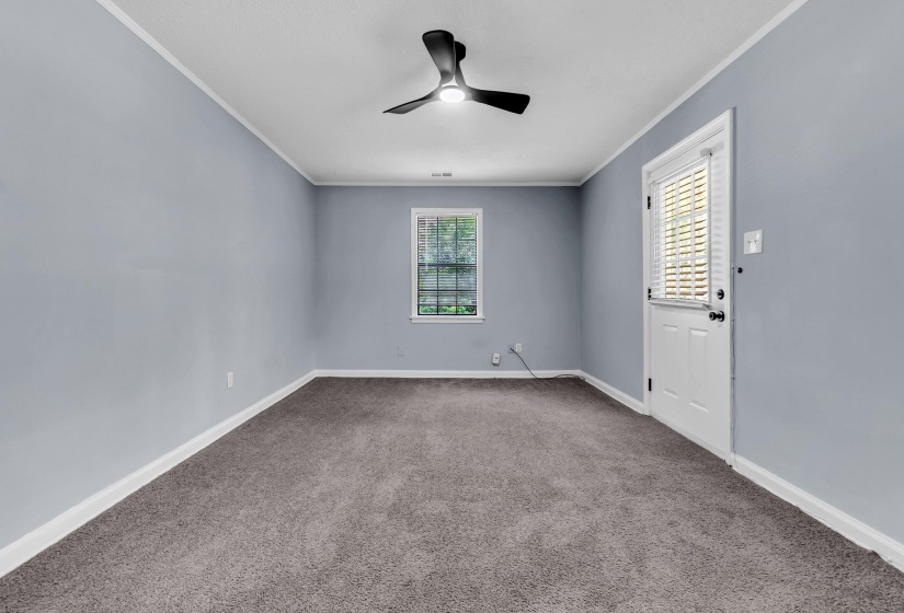 Neutral-toned room featuring a ceiling fan with integrated lighting, a window, and a white door with blinds