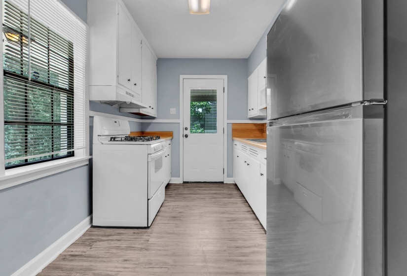 Kitchen featuring white cabinetry, wood-finish countertops, and wood-finish flooring