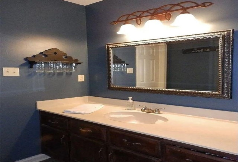 Bathroom vanity featuring a light-toned countertop, undermount sink, and dark wood-finish cabinetry