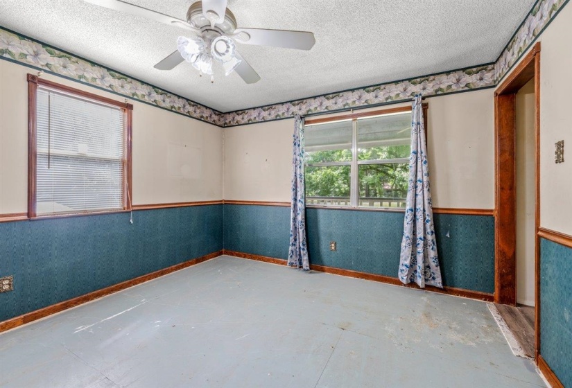 Room featuring two windows with wood-finish trim, a ceiling fan with integrated lighting, and painted flooring