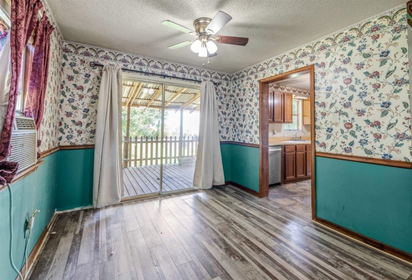Interior room featuring wood-finish flooring, a ceiling fan with light fixture, and a sliding glass door providing access to a covered outdoor deck