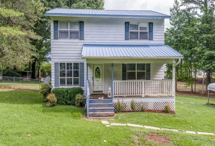 Two-story residence featuring white siding, a blue metal roof, and a covered front porch with white railing