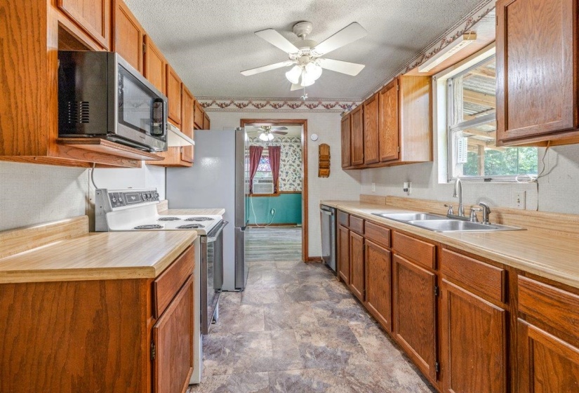 Kitchen featuring wood-finish cabinetry, a double basin stainless steel sink, and a ceiling fan