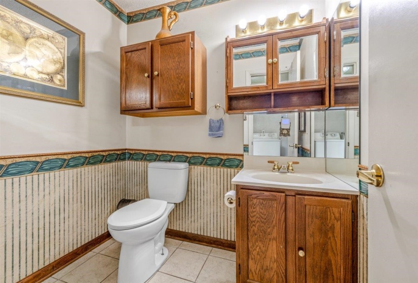 Bathroom featuring a single vanity with a white countertop and brass-finish faucet, accompanied by a mirrored medicine cabinet