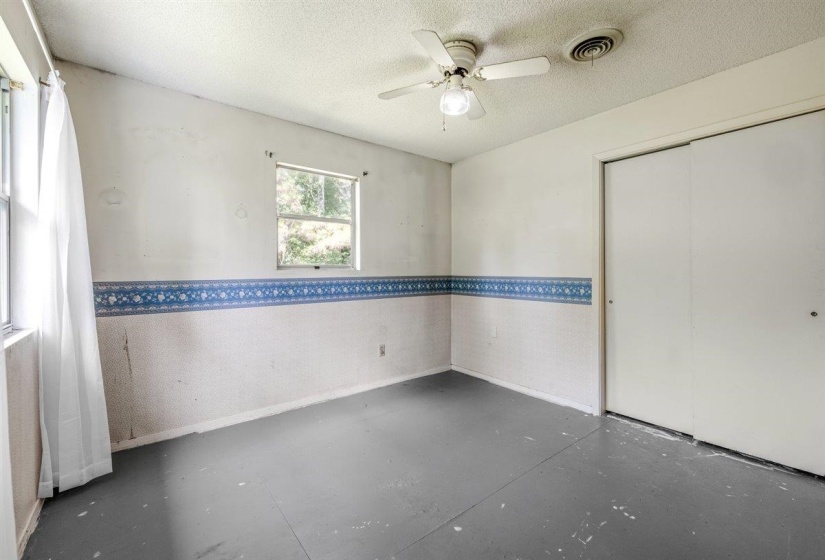 Room featuring a ceiling fan, dual windows, and sliding closet doors