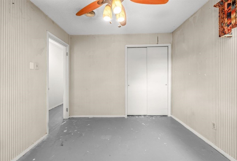 Room with textured striped wallpaper, a white ceiling, and a ceiling fan with light fixture
