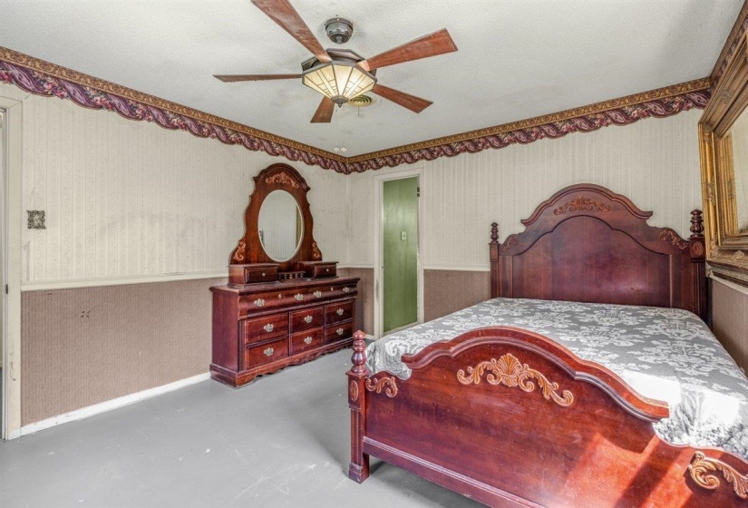 Room featuring a ceiling fan with integrated lighting, a green painted interior door, and walls with patterned wallpaper and a decorative border