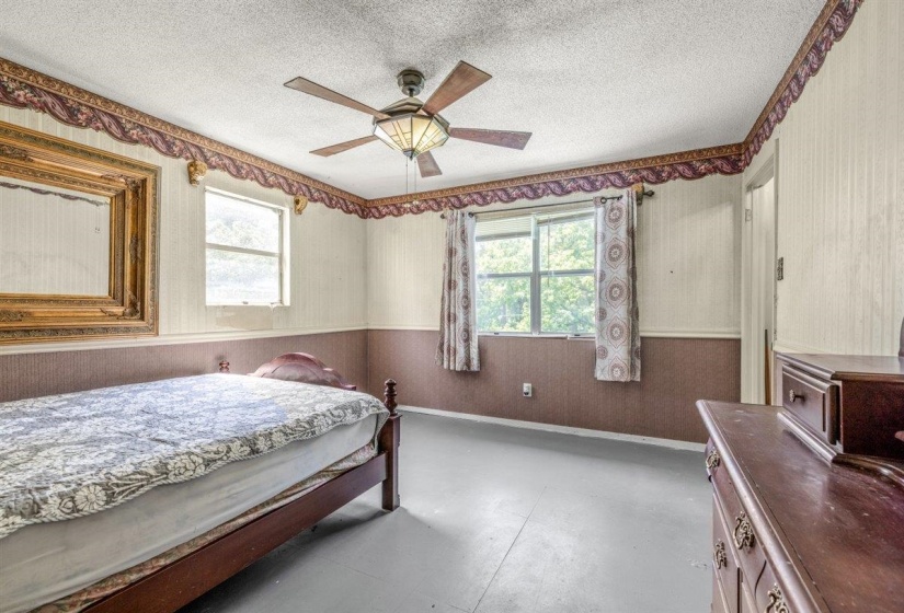 Interior room featuring a ceiling fan with integrated lighting, two windows, and textured wall coverings