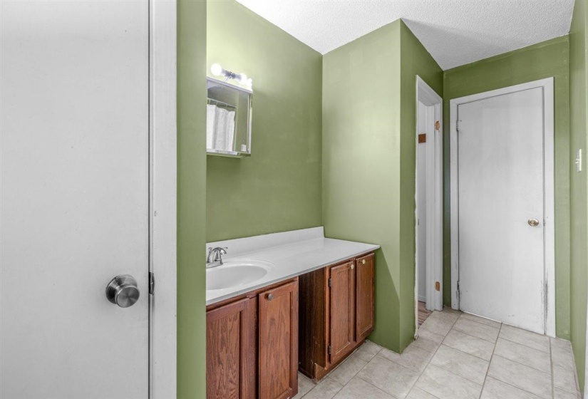 Bathroom vanity with a white countertop and integrated sink, under-cabinet storage, and an illuminated medicine cabinet