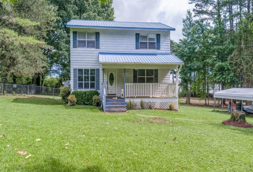 Two-story residence featuring a blue metal roof, white siding, and a covered front porch with white railing