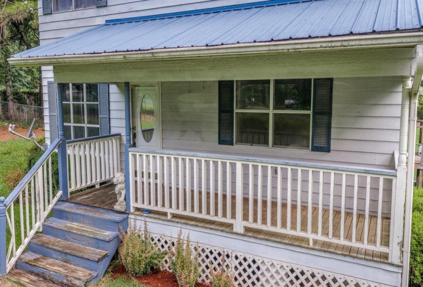 Front porch entry featuring a blue metal roof, white siding, and a white railing