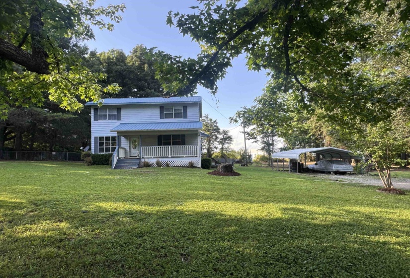 Two-story residence featuring light blue siding, a blue metal roof, and a covered front porch with white railings