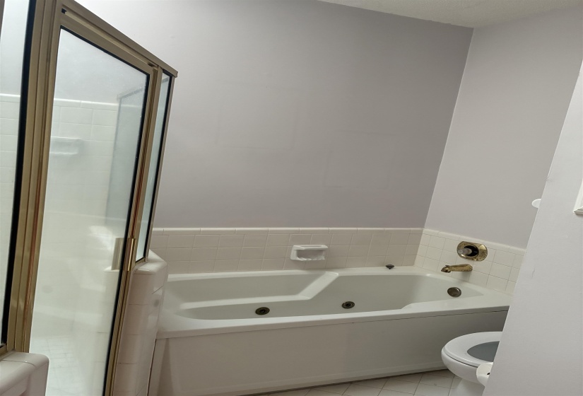 White soaking tub with integrated jets and gold-tone fixtures