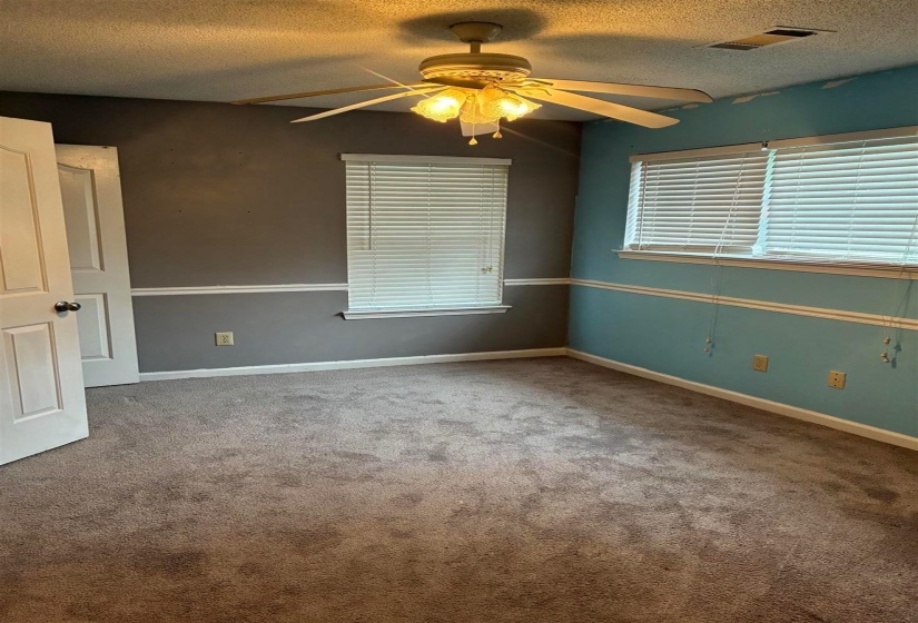 Carpeted room with a ceiling fan light fixture, two windows with blinds, and white trim molding