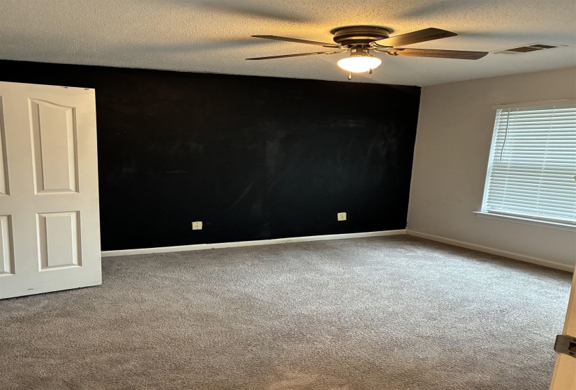 Carpeted room featuring a ceiling fan with integrated lighting, a window with horizontal blinds, and a paneled interior door