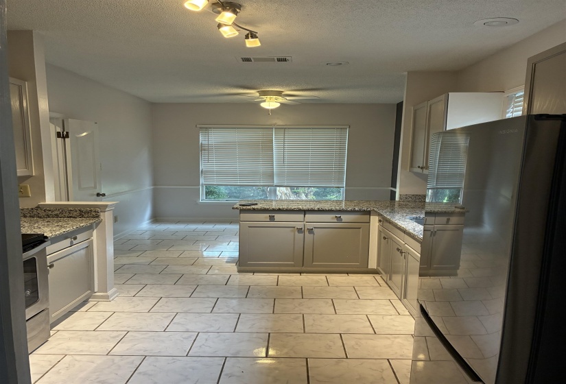 Kitchen with L-shaped granite countertops, light gray cabinetry, and tile flooring