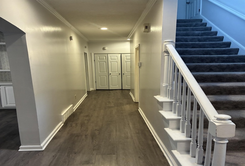Hallway featuring wood-finish flooring, recessed lighting, white crown molding, and white baseboards