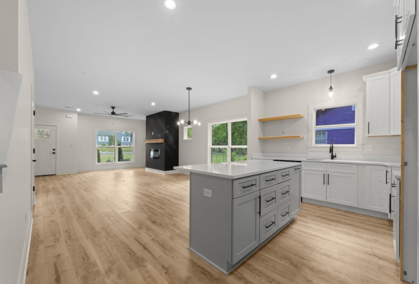 Kitchen with open floor plan, a center island, suspended lighting, open shelves, and light wood-style floors