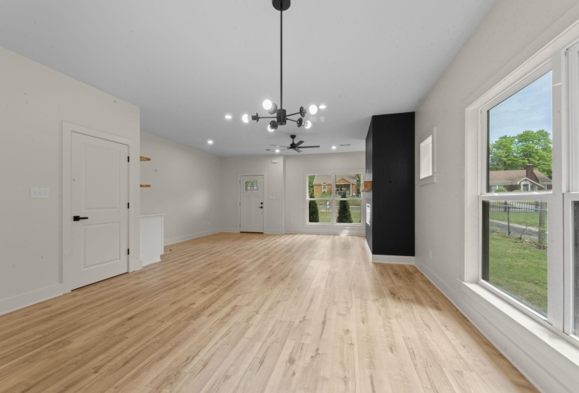 Unfurnished living room with light wood-style floors, ceiling fan, and suspended lighting