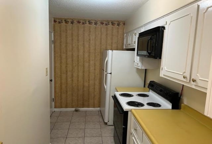 Kitchen featuring white cabinetry, a black over-the-range microwave, a white electric range, and light-colored countertops