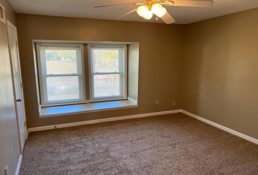 Carpeted room featuring a double window with a built-in sill, a ceiling fan with integrated lighting, and neutral-toned walls
