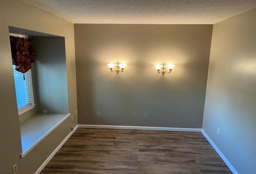 Interior space featuring wood-finish flooring, two wall sconces, a window niche with a built-in bench, and neutral-toned walls