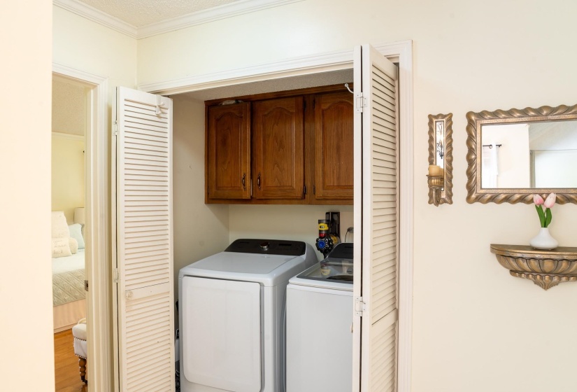 Laundry closet featuring bi-fold louvered doors and wood cabinetry
